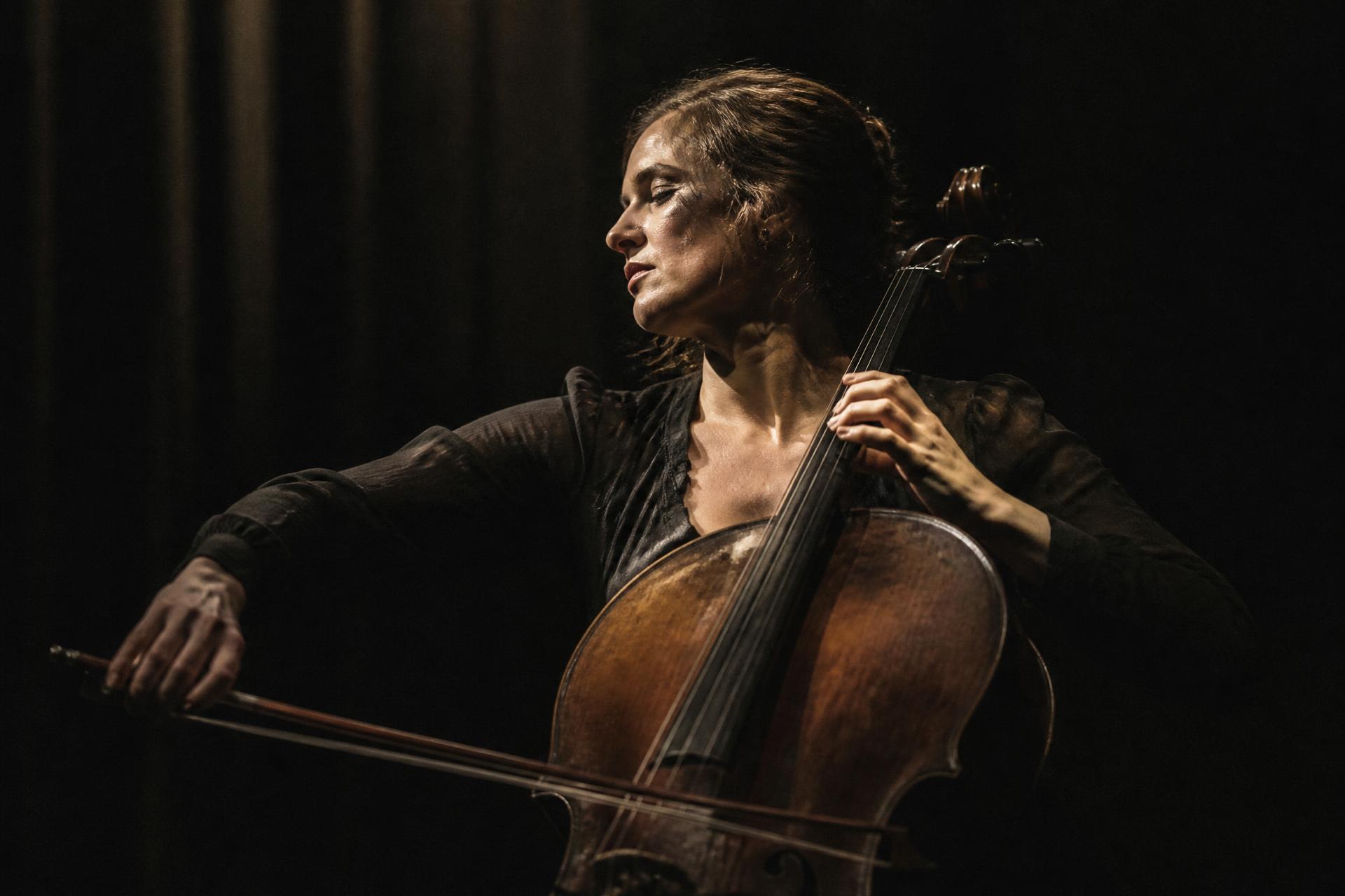 A cellist performing alone under a single stage light